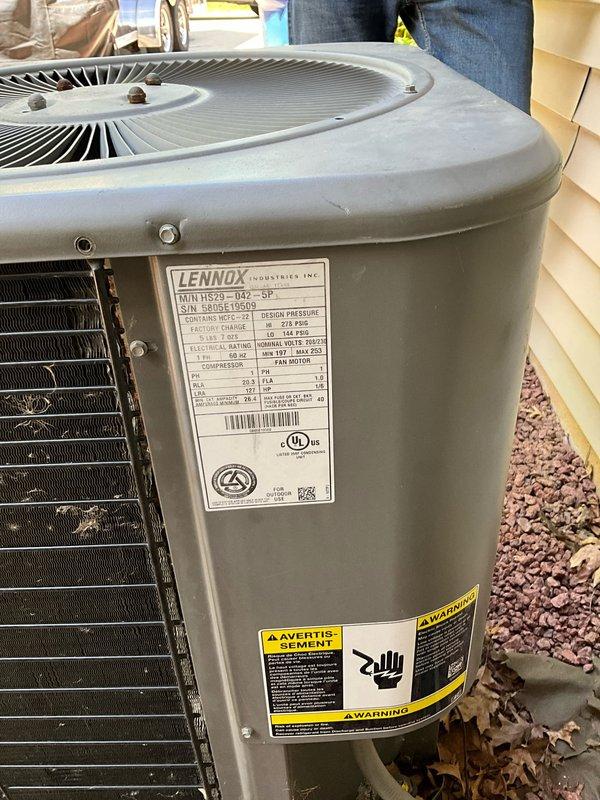 Conducted on-site evaluation for complete HVAC system replacement at residential property with existing Lennox equipment. Customer currently operating a natural gas furnace located in basement with outdoor air conditioning condenser unit. System serves a three-zone configuration requiring proper equipment sizing and compatibility.

Assessed current equipment specifications and determined replacement requirements of 110,000 BTU furnace capacity and 4-ton air conditioning unit to adequately serve the home's heating and cooling demands across all three zones. Photographically documented existing Lennox outdoor condenser unit, noting manufacturer labels, technical specifications, warning decals, and overall equipment condition. Unit positioned against exterior wall with heat exchanger fins visible and accessible for inspection.

Examined internal wiring configuration and electrical connections within existing equipment, documenting wire routing, color coding, and component connections for 