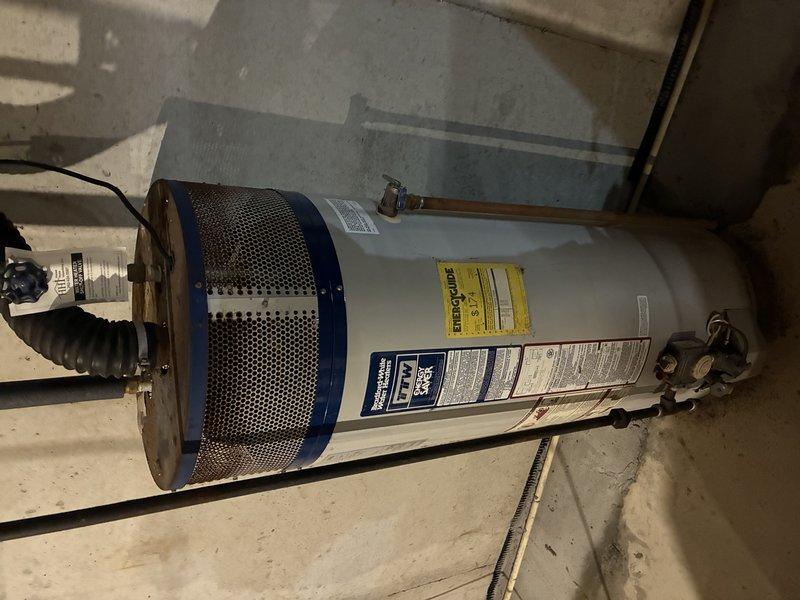 Responded to service call for non-recycling water softener experiencing calcium buildup and clogging issues. Performed diagnostic inspection of water treatment system and associated plumbing infrastructure including copper supply lines, PVC discharge piping, and control valve assembly. Evaluated system operability and documented current condition of equipment with photographic evidence showing piping configuration, mounting hardware, and overall installation setup in utility area.
