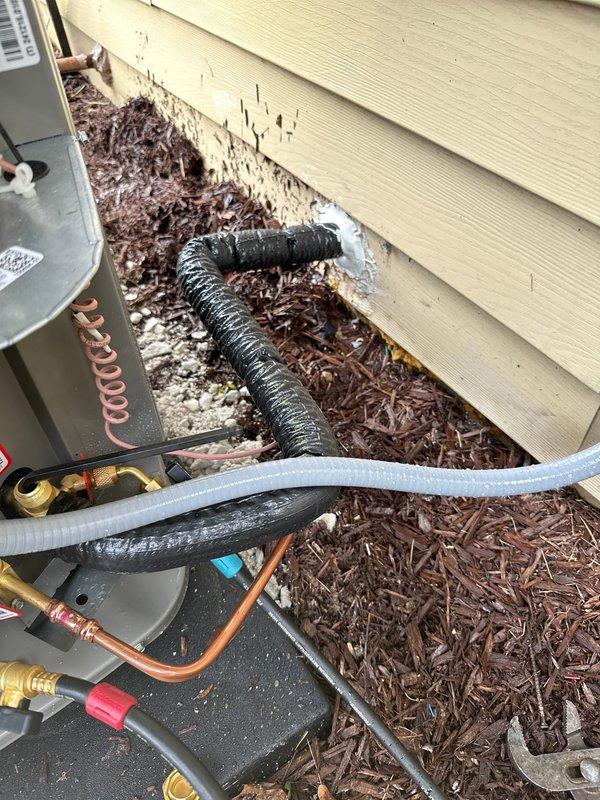 Completed installation of new Lennox EL16KF air conditioning system with matching evaporator coil and 35-foot refrigerant line set at residential property. Unit installed on exterior foundation pad against building with yellow vinyl siding, all refrigerant lines properly insulated and secured, system charged with R-454B refrigerant per manufacturer specifications, and all electrical connections completed to code. Installation tested and verified operational with proper airflow and cooling performance.