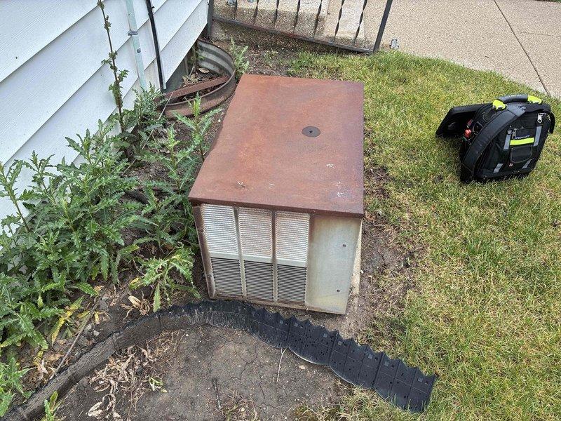 Responded to no cooling call on aging outdoor condensing unit that failed over the weekend with abnormal noise reported. Upon arrival, found heavily weathered unit with significant rust deterioration on top panel and overgrown vegetation restricting airflow around cabinet. Performed diagnostic evaluation to determine cause of cooling failure and unusual operational sounds. Documented unit condition showing extensive exterior corrosion and lack of maintenance clearance around equipment. Customer notified of findings for repair options on system exceeding 10-year service life.