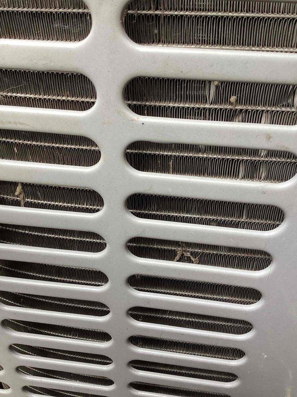 Responded to no cooling call on aging residential air conditioning system. Upon arrival, performed diagnostic inspection of outdoor condensing unit. Found evaporator coil heavily blocked with organic debris and deteriorated material that had accumulated around and within the unit, severely restricting airflow through the heat exchanger fins. The obstruction prevented proper heat transfer and caused system shutdown. Cleaned accessible debris from exterior of unit and documented coil condition. Advised customer that the evaporator coil requires professional cleaning or replacement due to age-related deterioration and blockage. System is over ten years old and showing signs of wear consistent with its age. Recommended evaluation of complete system for potential replacement given age and current condition of components.