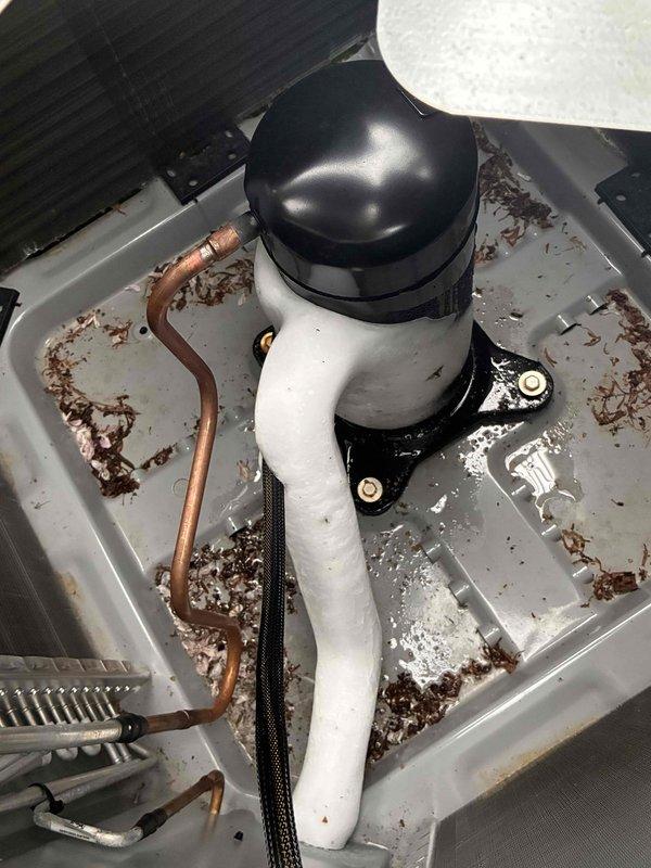 Responded to callback for recently installed AC system not cooling properly. Upon inspection, discovered evaporator coil completely frozen over with extensive ice buildup throughout the unit. Found drain pan filled with debris and moisture, indicating airflow restriction. Identified inadequate airflow as root cause of freezing condition. Documented conditions with photos showing ice accumulation on coil and contaminated drain pan. System requires defrosting, airflow correction, and verification of proper refrigerant charge once ice melts.