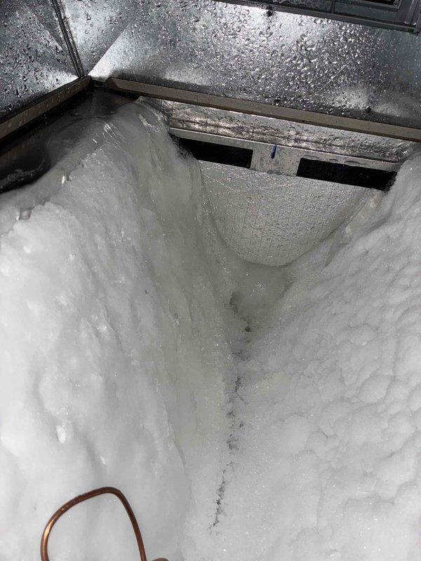Responded to callback for recently installed AC system not cooling properly. Upon inspection, discovered evaporator coil completely frozen over with extensive ice buildup throughout the unit. Found drain pan filled with debris and moisture, indicating airflow restriction. Identified inadequate airflow as root cause of freezing condition. Documented conditions with photos showing ice accumulation on coil and contaminated drain pan. System requires defrosting, airflow correction, and verification of proper refrigerant charge once ice melts.
