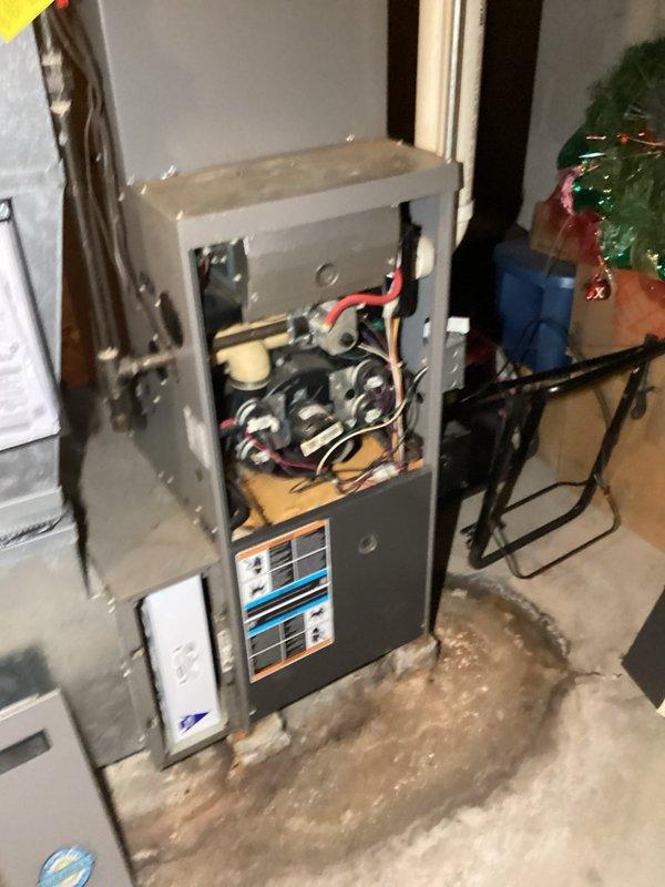Responded to no cooling complaint on aging HVAC system. Upon arrival, performed diagnostic inspection of both indoor furnace unit and outdoor condensing units. Accessed furnace cabinet to inspect internal components, electrical connections, and control systems. Evaluated outdoor equipment condition, noting two condensing units present at property with vegetation growth around units affecting airflow. Completed system assessment and documented equipment condition with photos for service records.