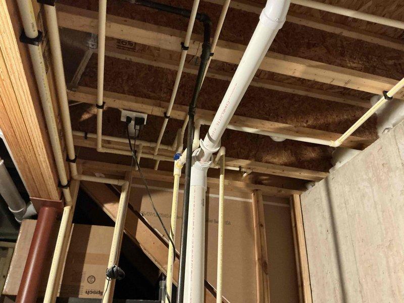 Conducted estimate for water heater replacement due to active leak in existing unit. Assessed plumbing infrastructure including PVC drainage lines, supply piping, and ceiling-mounted utility systems in unfinished space to determine replacement requirements and accessibility for installation.