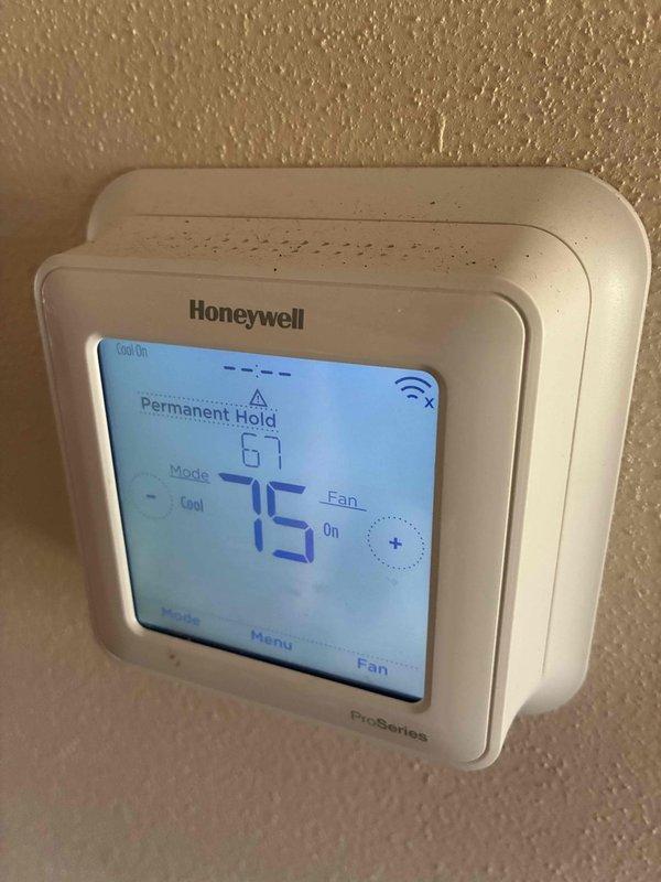 Responded to no cooling call on commercial AC unit. Upon inspection, found system running but not producing cool air. Diagnosed issue as failed compressor due to internal mechanical failure, evidenced by corroded and mineral-stained service port fittings. Thermostat showing permanent hold at 75°F with cooling mode active but unable to satisfy setpoint. Advised customer of compressor replacement requirement to restore cooling function.
