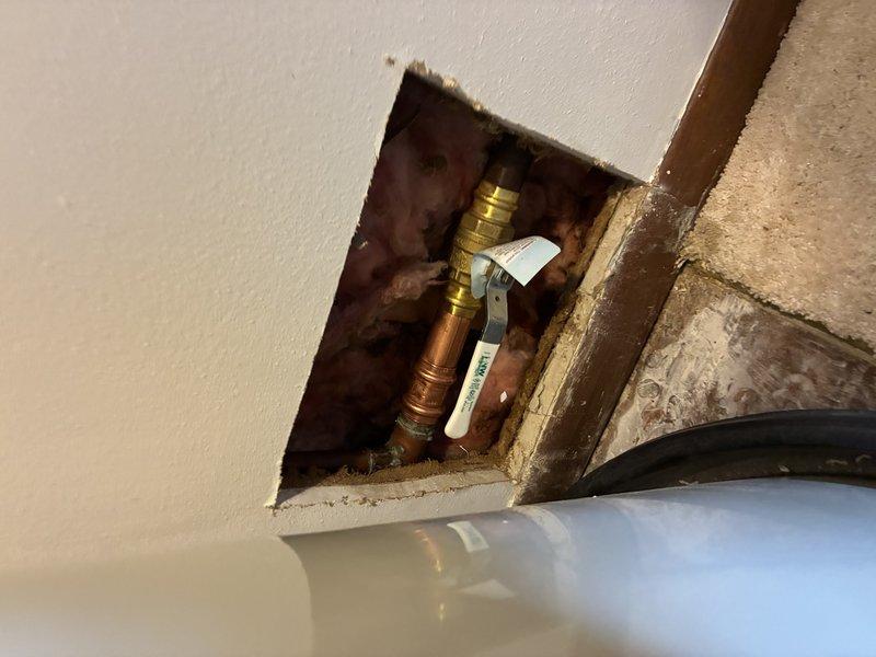 Completed shower/tub plumbing installation involving access point modifications to existing wall cavities. Cut access openings in drywall to reach supply lines, installed new shut-off valves with brass fittings and copper pipe connections, and integrated plumbing assembly at wall-ceiling junction. Addressed water-damaged framing during installation and secured all valve mechanisms for proper operation.