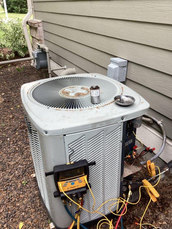 Responded to no cooling complaint on residential air conditioning system. Upon arrival, found outdoor condensing unit inoperative. Visual inspection revealed heavily corroded dual run capacitor with rust damage on terminal connections and cap, along with significant debris accumulation on condenser fan grille. Connected manifold gauge set to system for diagnostic testing. Determined failed capacitor was preventing compressor and condenser fan motor from starting. Replaced defective capacitor with new PROTECH unit, ensuring proper electrical connections and secure mounting. Cleaned debris from condenser fan grille to restore adequate airflow. Cycled system on, verified compressor and fan motor operation, and confirmed proper refrigerant pressures. System restored to normal cooling operation.