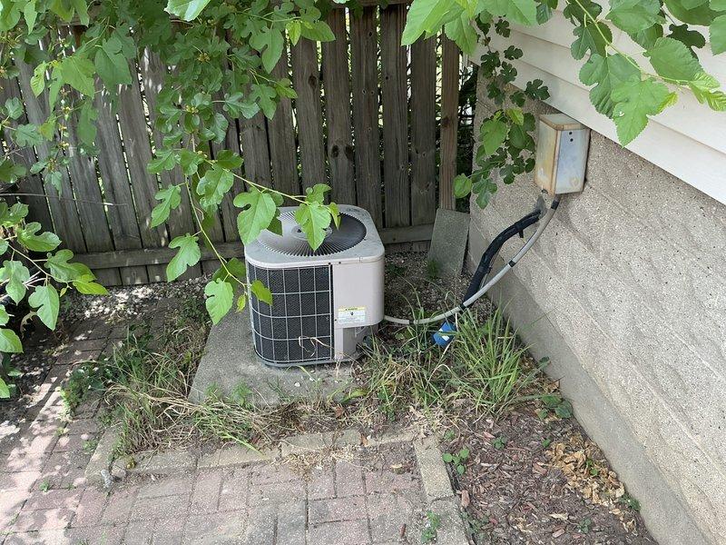 Responded to no cooling call and found outdoor condenser unit not operating. Upon inspection, discovered electrical disconnect had been pulled, preventing power to the system. Assessed both outdoor condenser unit positioned against wooden fence and indoor air handler/furnace system in basement. Documented existing HVAC equipment configuration including outdoor unit with electrical disconnect mounted on foundation wall and indoor metal furnace with associated ductwork. Provided comprehensive estimate for complete HVAC system replacement to address cooling failure and upgrade aging equipment.