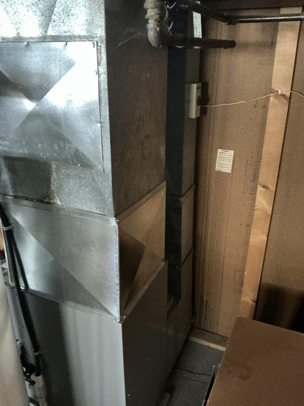 Responded to no cooling call and found outdoor condenser unit not operating. Upon inspection, discovered electrical disconnect had been pulled, preventing power to the system. Assessed both outdoor condenser unit positioned against wooden fence and indoor air handler/furnace system in basement. Documented existing HVAC equipment configuration including outdoor unit with electrical disconnect mounted on foundation wall and indoor metal furnace with associated ductwork. Provided comprehensive estimate for complete HVAC system replacement to address cooling failure and upgrade aging equipment.