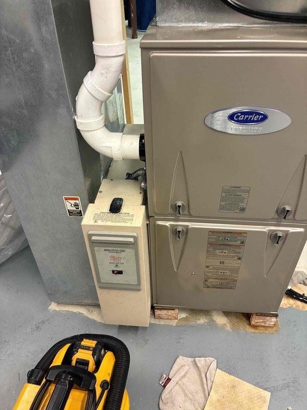 Responded to no cooling call on 10-year-old Carrier HVAC system for new homeowners requesting warranty coverage verification. Upon arrival, performed system inspection and diagnostics on furnace/air handler unit installed in mechanical room. During examination, discovered compromised condensate drain system with corroded brass manifold assembly showing significant age-related deterioration, discoloration, and moisture accumulation on surrounding components. The drainage hardware exhibited brown staining and corrosion at connection points, indicating potential blockage or drainage failure contributing to system malfunction. Inspected PEX tubing connections and drain line routing from unit. Documented equipment condition and warranty-eligible components with photographic evidence for manufacturer claim submission. System requires condensate drain assembly replacement to restore proper operation and prevent future cooling interruptions.