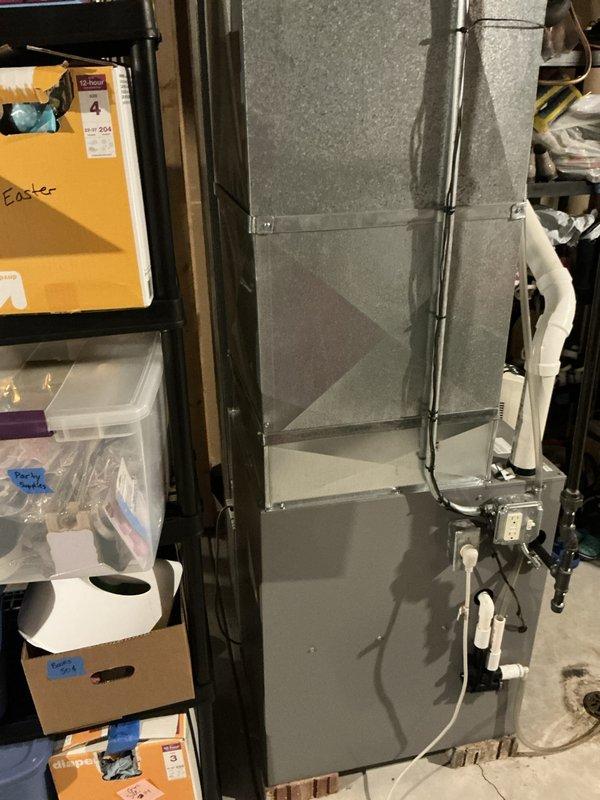 Responded to emergency HVAC service call to assess air conditioning system and furnace replacement needs in basement utility area. Documented existing ductwork configuration, electrical connections, and identified water drainage concerns around floor drain that may impact equipment installation and longevity.