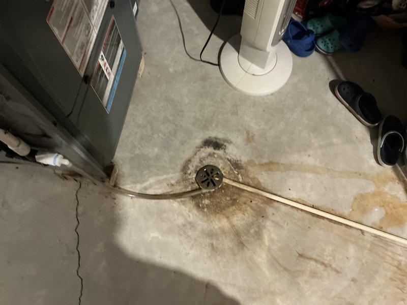 Responded to emergency HVAC service call to assess air conditioning system and furnace replacement needs in basement utility area. Documented existing ductwork configuration, electrical connections, and identified water drainage concerns around floor drain that may impact equipment installation and longevity.
