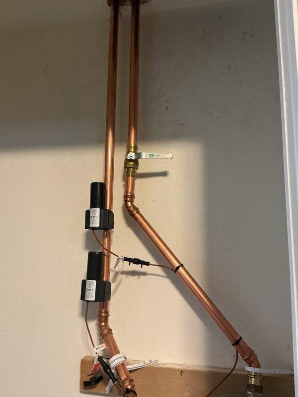 Completed installation of new water meter and associated piping system. Installed vertical copper piping configuration with brass ball valves, expansion tanks, and monitoring equipment. Routed refrigerant lines along wall with proper support brackets and mounted sensors with electrical connections. All connections were brazed and tested for proper operation.