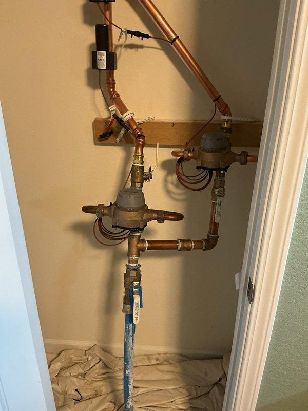 Completed installation of new water meter and associated piping system. Installed vertical copper piping configuration with brass ball valves, expansion tanks, and monitoring equipment. Routed refrigerant lines along wall with proper support brackets and mounted sensors with electrical connections. All connections were brazed and tested for proper operation.
