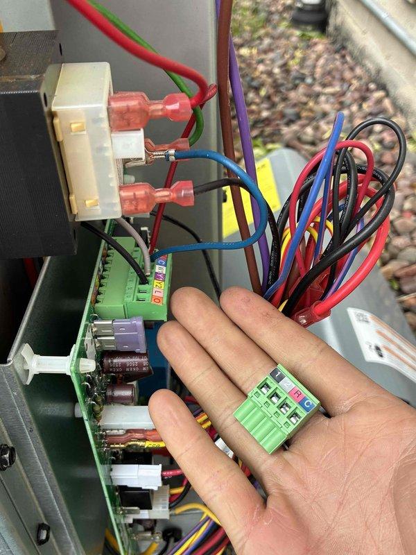 Completed warranty replacement of HVAC control board. Removed failed control board and terminal connector block from equipment housing, installed new replacement control board, and reconnected all electrical wiring including multi-conductor control wiring. Verified proper system operation with thermostat cycling cooling mode correctly, displaying 80°F current temperature with setpoint at 75°F. System restored to normal operation.