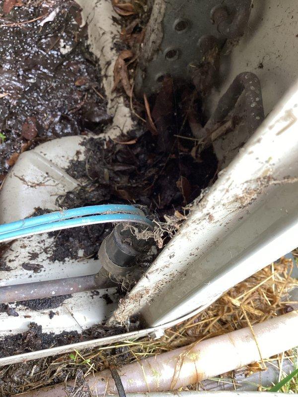 Responded to no cooling call on system over 10 years old. Upon arrival, inspected attic-mounted air handler unit and found motor component with visible wear and degraded condition. Evaluated outdoor condensing unit and drainage system, which showed significant debris accumulation, clogged drain lines, and restricted airflow around equipment. Cleared drain lines of organic matter and sediment buildup that was impeding proper condensate removal. System required comprehensive assessment of aging components to restore cooling functionality.