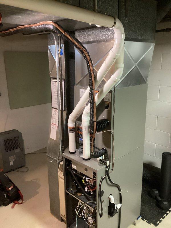 Completed full HVAC system installation including new furnace and air conditioning equipment in basement mechanical room. Installation performed with proper permitting and licensed electrician coordination, featuring light green air handler unit, heating furnace, refrigerant line connections with insulation, PVC condensate drainage, and integrated ductwork. All components professionally installed to manufacturer specifications with proper electrical connections, refrigerant lines routed and insulated, and system tested for operation.