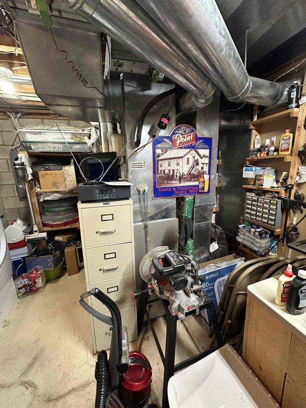 Conducted furnace replacement estimate in residential basement utility area. Evaluated existing beige furnace unit with overhead silver ductwork and white PVC condensate piping, documenting current system configuration and mechanical room layout for complete HVAC system replacement proposal.