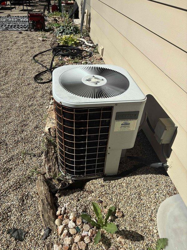 Conducted on-site estimate for complete HVAC system replacement including gas furnace currently located in basement and outdoor air conditioning condenser unit. Evaluated existing equipment condition, documented current installation with photographs showing AC unit positioned on concrete pad with gravel landscaping against building exterior, and provided homeowner with replacement options and specifications for both heating and cooling systems.