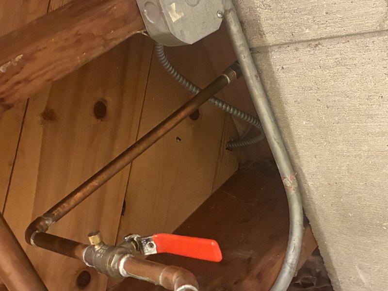 Responded to service call for leaking exterior hose faucet. Upon inspection, identified compromised ball valve with red handle connected to copper supply line in utility area. Valve exhibited signs of wear and active leak at connection point. Assessed existing copper piping configuration, including vertical runs and 90-degree elbow joints. Determined replacement of ball valve assembly was necessary due to extent of deterioration. Completed diagnostic evaluation of plumbing system to verify proper water flow and pressure post-repair recommendations.