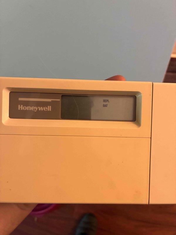 Responded to no cooling call with blank thermostat display. Found Honeywell thermostat showing low battery warning despite customer replacing batteries. Diagnosed failed thermostat unit, removed old device from wall, exposed and prepared wiring connections, and installed replacement thermostat to restore system operation and cooling functionality.
