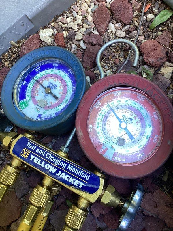 Responded to no cooling complaint on residential split system with air handler located in attic. Upon arrival, found thermostat inoperative and system previously shut down. Connected manifold gauges to outdoor condensing unit to verify system pressures and diagnose cooling failure. Determined thermostat malfunction was preventing system operation and addressed issue to restore normal cooling function.