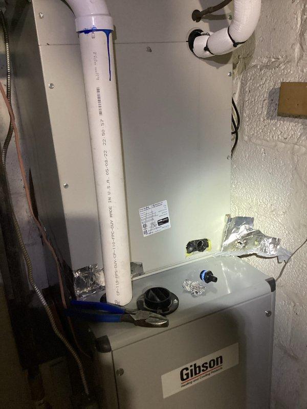 Responded to service call for continuous dripping from indoor evaporator coil on Gibson air handler unit located in attic space. Upon inspection, confirmed active condensate leak from 5-6 year old indoor coil assembly. Documented existing system conditions including air handler installation, condensate drain line configuration with PVC piping and securing straps, and outdoor condensing unit positioned on concrete pad with proper clearances. Photographed equipment and leak source for service records and provided recommendations for repair options to address the continuous drip issue affecting the HVAC system performance.