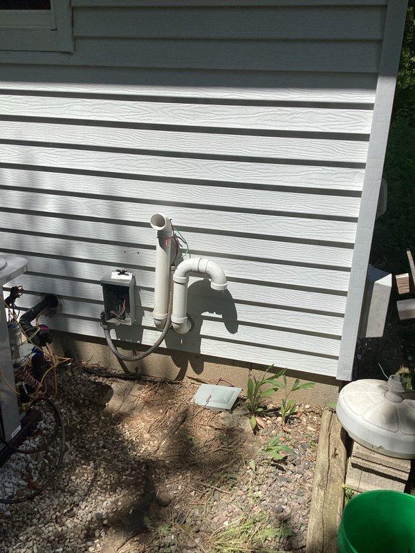 Completed full HVAC system installation including new furnace and air conditioning condenser unit positioned on concrete pad with proper refrigerant line connections and electrical hookup. Installed new registers throughout the home, ran fresh ductwork for bathroom exhaust fan ventilation, and completed condensate drain system with PVC piping and exterior discharge line mounted to building exterior.