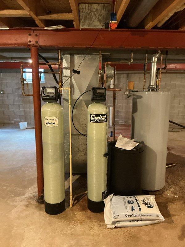 Completed installation of dual-tank Capital water softener system and Iron Curtain filtration unit in basement utility area. Systems were plumbed with copper piping, control heads mounted and programmed, and all connections pressure-tested for leaks. Equipment is fully operational and ready for service.