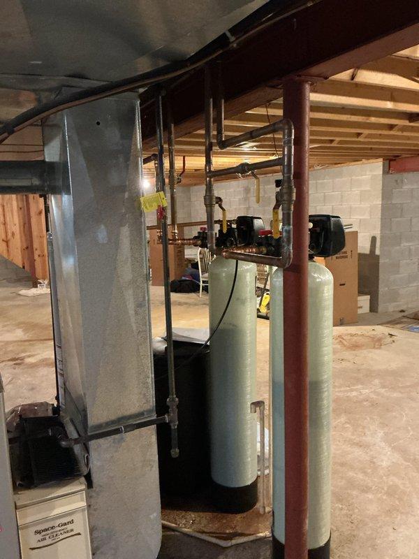 Completed installation of dual-tank Capital water softener system and Iron Curtain filtration unit in basement utility area. Systems were plumbed with copper piping, control heads mounted and programmed, and all connections pressure-tested for leaks. Equipment is fully operational and ready for service.