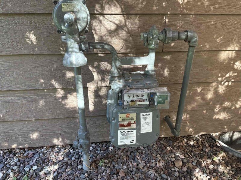 Conducted on-site evaluation for generator installation estimate in residential backyard location. Assessed existing natural gas meter assembly and infrastructure to determine feasibility and requirements for generator connection. Documented current gas metering equipment, piping configuration, and available installation space adjacent to property fence line for proper equipment placement and code compliance.