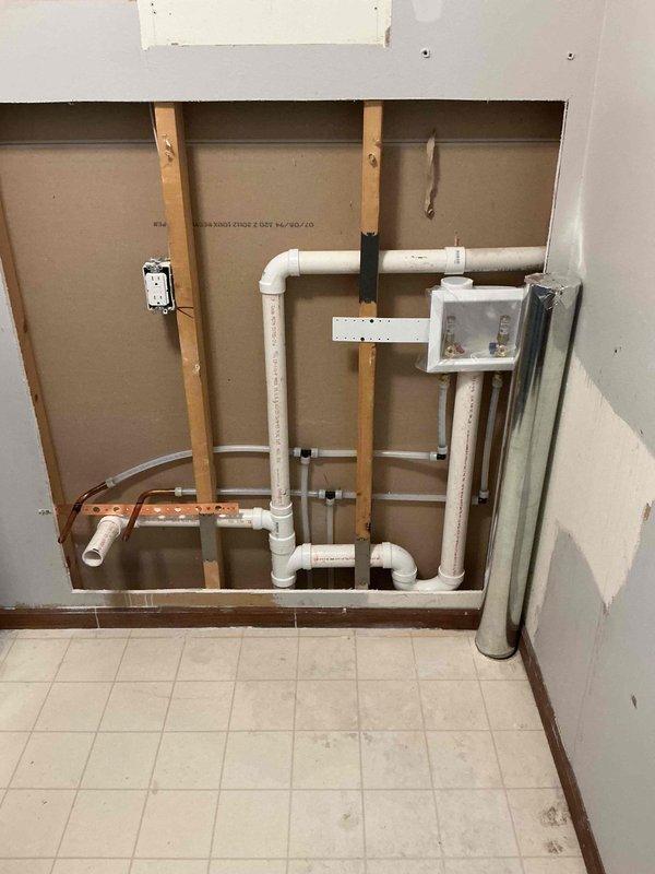 Relocated laundry connections and dryer vent per estimate specifications. Successfully rerouted white PVC drain lines and water supply piping through wall cavities and ceiling joists, securing all pipes with appropriate mounting brackets and straps to structural framing. Modified copper supply lines and installed new junction boxes to accommodate the repositioned laundry equipment location.