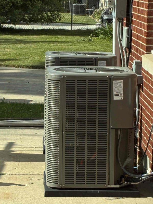 Responded to service call for lower duplex air conditioning unit experiencing short cycling issues. Upon arrival, performed diagnostic assessment of dual condensing unit installation located on exterior concrete pad. Evaluated system operation and identified intermittent on/off cycling concern reported by occupant.

Conducted thorough inspection of outdoor condensing units, checking electrical connections, refrigerant lines, and control components. Verified proper mounting and installation integrity of both units on shared concrete pad. Inspected conduit runs and copper line sets along exterior wall for any signs of damage or loose connections that could contribute to cycling problems.

Performed refrigerant charge verification using calibrated digital scale to ensure proper system charge levels. Checked for potential refrigerant loss or contamination that could cause compressor short cycling. Inspected both condensing units for signs of weathering, corrosion, or component degradation 