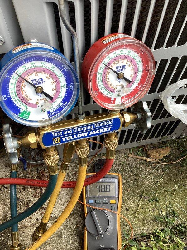 Responded to no cooling complaint on 10+ year old system. Connected manifold gauges and performed refrigerant pressure diagnostics while monitoring electrical readings with multimeter showing 4.88 measurement at outdoor condensing unit. System evaluation completed to determine cooling capacity issues.