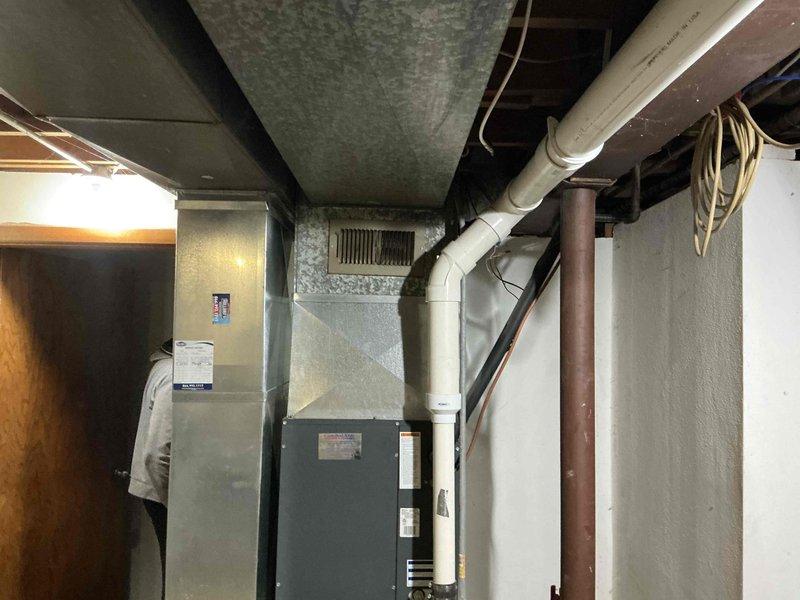 Conducted comprehensive assessment of existing natural gas furnace system located in basement mechanical room for replacement estimate. Evaluated current HVAC unit configuration, existing ductwork connections, PVC venting system, and electrical supply routing. Documented equipment specifications, installation clearances, and mechanical infrastructure including gas line accessibility and condensate drainage setup. Reviewed basement utility space layout with exposed ceiling joists, support structures, and existing ventilation components to determine optimal replacement equipment specifications and installation requirements.