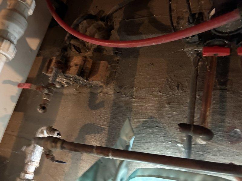 Responded to emergency plumbing service call following property break-in where all copper piping had been stripped from the residential system. Conducted comprehensive assessment of the property to document the extent of damage and determine scope of restoration work required. The theft included complete removal of copper supply lines servicing the water heater, water softener, exterior hose bibs, and furnace connections.

Inspected remaining plumbing infrastructure and mechanical equipment to evaluate salvageable components and identify all connection points requiring replacement. Documented existing water heater installation showing oxidized copper piping remnants, metallic tape insulation at junction points, and mounting hardware still in place. Examined underside of water heater tank, noting remaining PVC drain connections, flexible supply lines, and corroded pipe stubs where copper had been cut away.

Assessed mechanical room conditions including white painted surfaces showing acc
