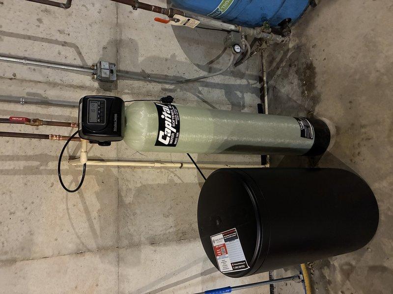 Installed complete residential water softening system in basement utility area, including Craven-branded fiberglass softener tank with digital control head and accompanying brine tank for salt storage. Connected system to existing copper supply lines with appropriate valves and fittings, mounted electronic control unit with timer display, and verified proper integration with overhead plumbing infrastructure including pressure tank. System tested and operational upon completion.