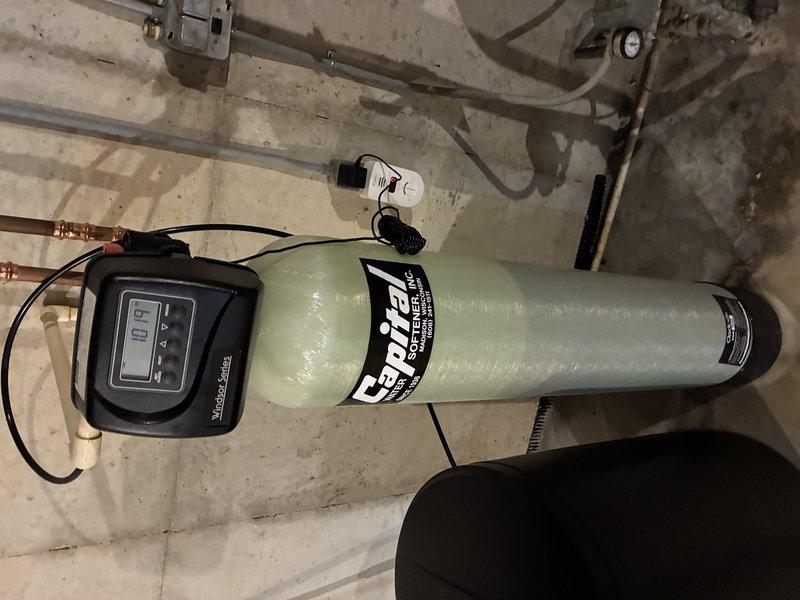 Installed complete residential water softening system in basement utility area, including Craven-branded fiberglass softener tank with digital control head and accompanying brine tank for salt storage. Connected system to existing copper supply lines with appropriate valves and fittings, mounted electronic control unit with timer display, and verified proper integration with overhead plumbing infrastructure including pressure tank. System tested and operational upon completion.