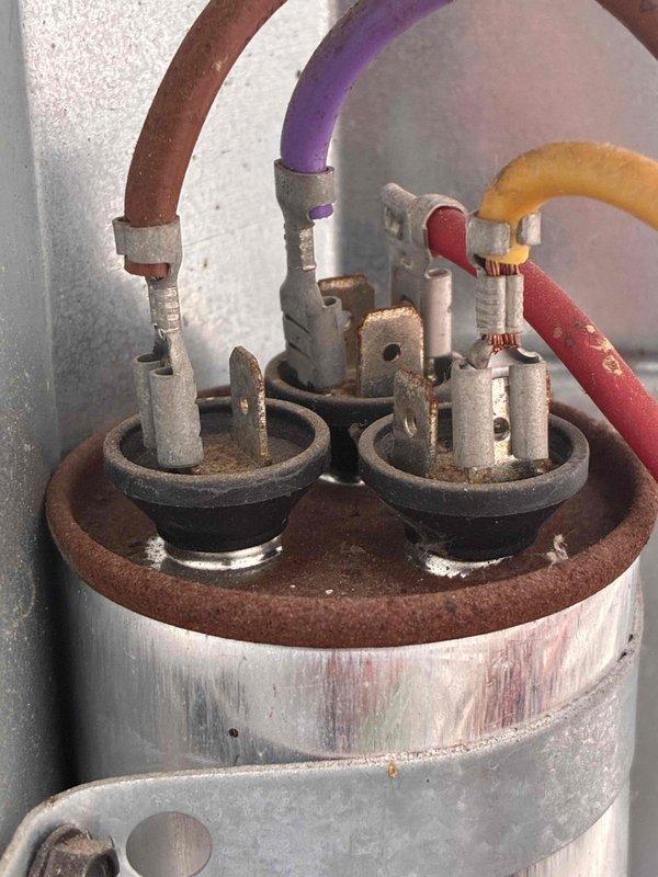 Completed comprehensive furnace and air conditioning tune-up maintenance. Inspected condenser unit and found coil fins with moderate debris accumulation including dust, dirt, and lint buildup between slats. Examined electrical connections on compressor capacitor, noting significant corrosion and insulation deterioration on multiple wire terminals, particularly on brown-colored conductor which displayed heavy oxidation. All components photographed for documentation purposes, and system operational status verified upon completion.