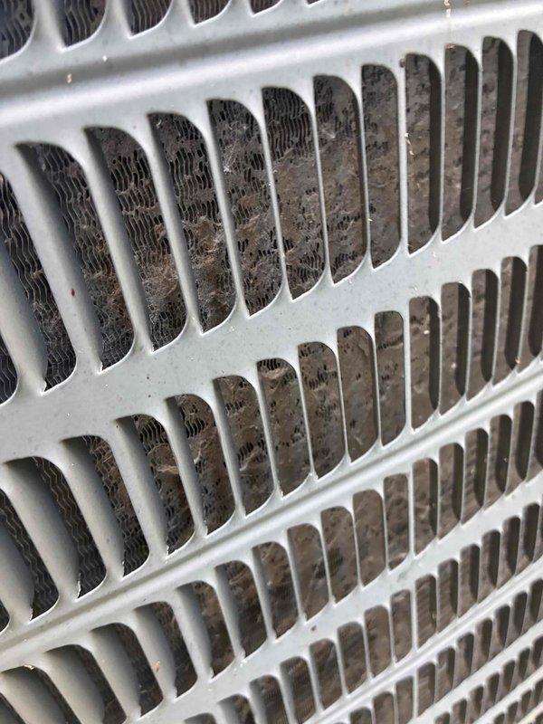 Completed comprehensive furnace and air conditioning tune-up maintenance. Inspected condenser unit and found coil fins with moderate debris accumulation including dust, dirt, and lint buildup between slats. Examined electrical connections on compressor capacitor, noting significant corrosion and insulation deterioration on multiple wire terminals, particularly on brown-colored conductor which displayed heavy oxidation. All components photographed for documentation purposes, and system operational status verified upon completion.