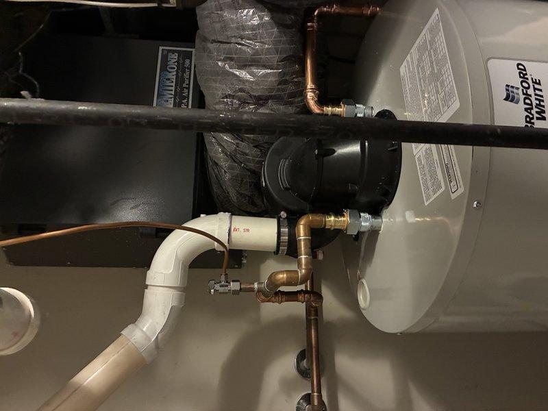 Completed installation of a 50-gallon short tank water heater (model PV12-4) in residential utility closet. Performed full system hookup including copper supply line connections with brass fittings, PVC drainage and temperature-pressure relief discharge piping, and proper tank securing with mounting straps. Installed associated components including expansion tank and verified all connections for proper operation and leak-free performance.