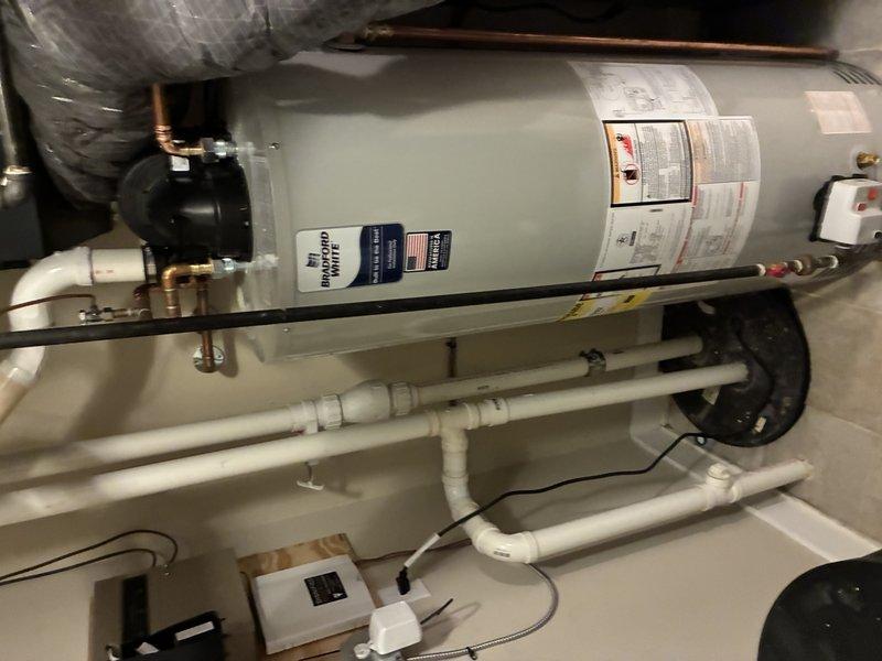 Completed installation of a 50-gallon short tank water heater (model PV12-4) in residential utility closet. Performed full system hookup including copper supply line connections with brass fittings, PVC drainage and temperature-pressure relief discharge piping, and proper tank securing with mounting straps. Installed associated components including expansion tank and verified all connections for proper operation and leak-free performance.