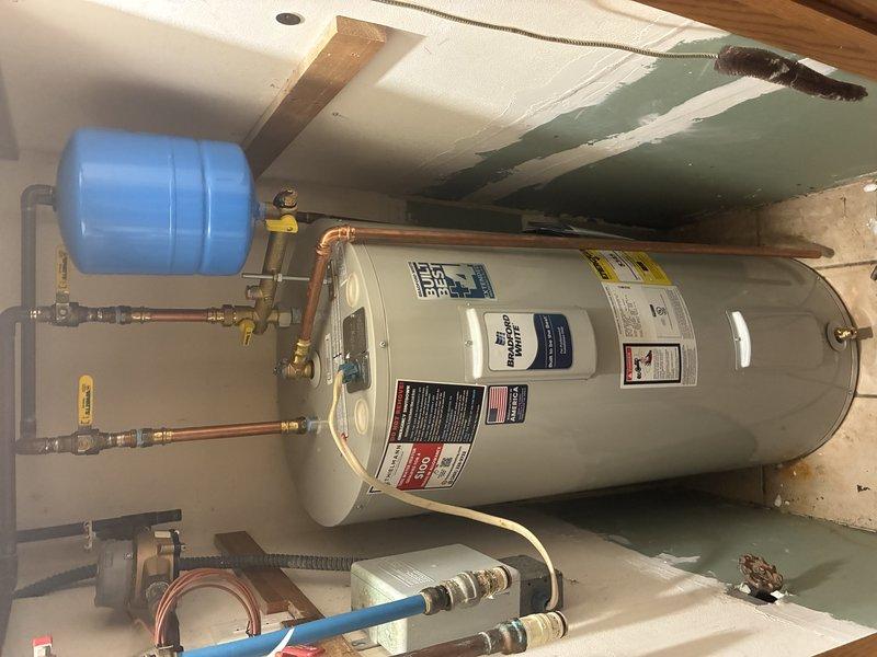 Completed installation of 40-gallon electric water heater in residential basement utility area. Installed new unit with proper plumbing connections using copper piping, brass fittings, and shut-off valves. Mounted blue expansion tank on wall and connected to system per code requirements. Configured all supply and discharge lines with appropriate flexible connectors at base of unit. Verified all electrical connections, tested system operation, and confirmed proper function of all components upon completion.