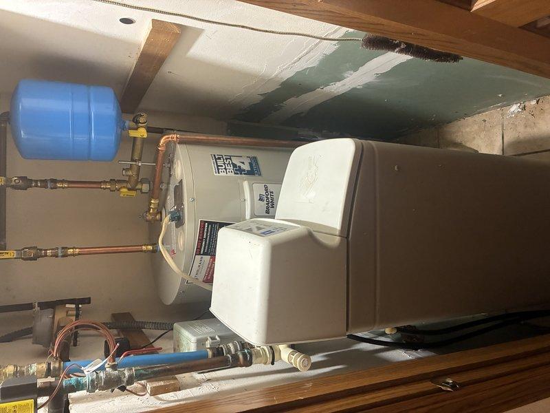 Completed installation of 40-gallon electric water heater in residential basement utility area. Installed new unit with proper plumbing connections using copper piping, brass fittings, and shut-off valves. Mounted blue expansion tank on wall and connected to system per code requirements. Configured all supply and discharge lines with appropriate flexible connectors at base of unit. Verified all electrical connections, tested system operation, and confirmed proper function of all components upon completion.