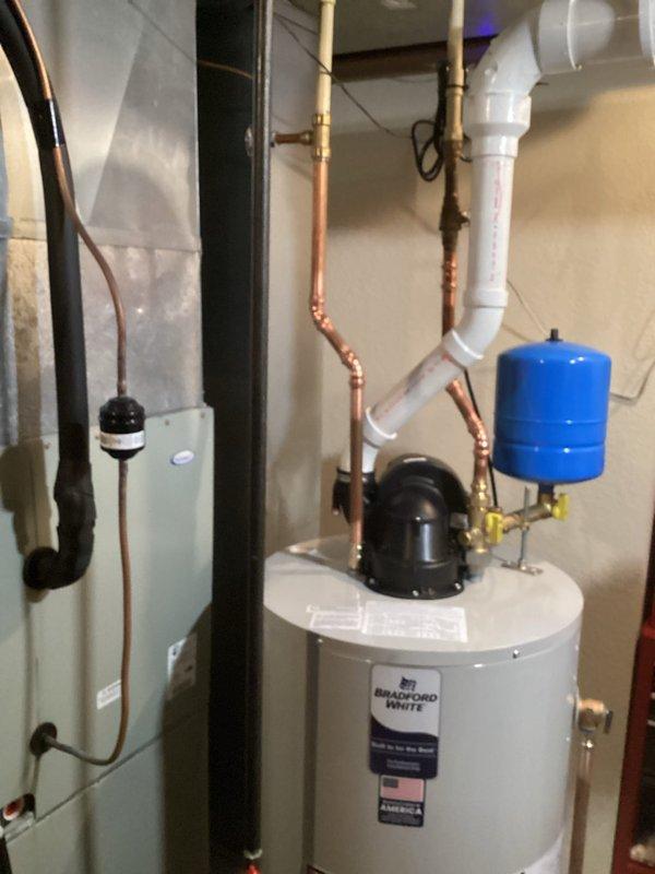 # Water Heater Installation

Successfully completed installation of a Bradford White residential water heater in basement utility area. Removed existing unit and installed new water heater per manufacturer specifications and local building codes. Connected domestic hot and cold water supply lines using copper piping with appropriate dielectric unions and brass fittings. Installed temperature and pressure relief valve with proper discharge piping termination. Connected blue thermal expansion tank to cold water supply line to accommodate system pressure fluctuations and prevent backflow into municipal water supply.

Configured all plumbing connections including shutoff valves for isolation and future service access. Verified proper venting configuration with black component assembly at top of unit. Ensured adequate clearances around water heater for combustion air and maintenance access per code requirements. Tested all connections for leaks using pressure testing procedures. Confirmed p