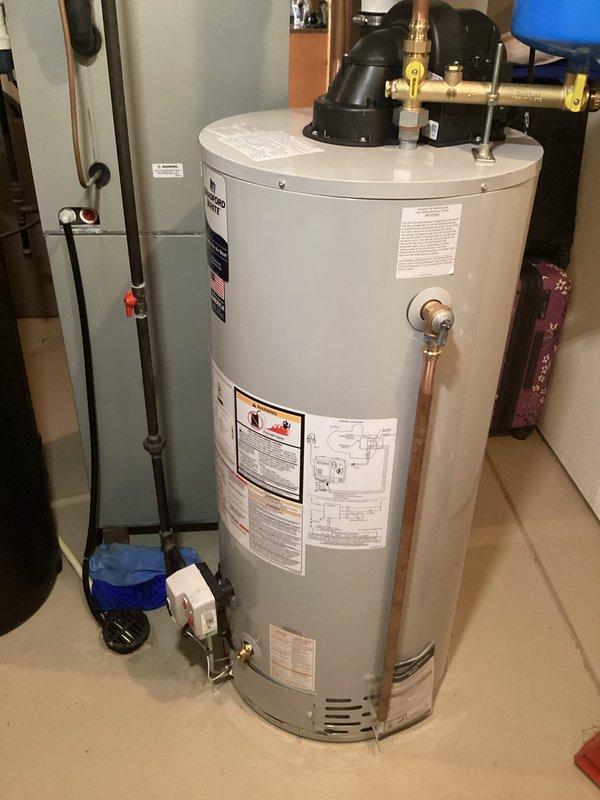 # Water Heater Installation

Successfully completed installation of a Bradford White residential water heater in basement utility area. Removed existing unit and installed new water heater per manufacturer specifications and local building codes. Connected domestic hot and cold water supply lines using copper piping with appropriate dielectric unions and brass fittings. Installed temperature and pressure relief valve with proper discharge piping termination. Connected blue thermal expansion tank to cold water supply line to accommodate system pressure fluctuations and prevent backflow into municipal water supply.

Configured all plumbing connections including shutoff valves for isolation and future service access. Verified proper venting configuration with black component assembly at top of unit. Ensured adequate clearances around water heater for combustion air and maintenance access per code requirements. Tested all connections for leaks using pressure testing procedures. Confirmed p