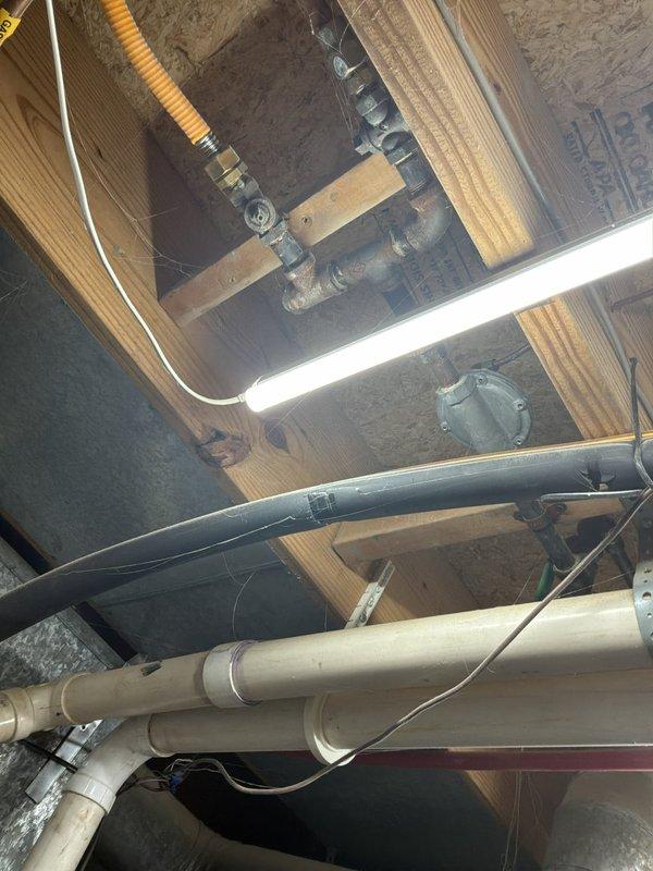 Completed estimate for installation of natural gas line from basement to outdoor grill location. Assessed existing gas infrastructure in basement crawl space, including current gas piping, shut-off valves, and routing options through floor joists. Evaluated exterior access point at wooden deck area where deck boards would require temporary removal to facilitate piping installation beneath deck structure to reach grill location. Documented existing conditions including current gas line configuration with yellow corrugated flexible connectors (CSST), rigid black iron pipe, and shut-off valve locations. Photographed proposed routing path through basement joists and exterior deck framing to determine material requirements and labor scope for approximately 10-12 feet of gas line installation.