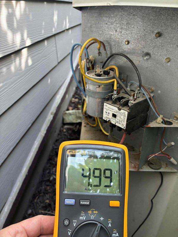 Responded to AC service call and performed diagnostic testing on outdoor condensing unit. Used digital multimeter to measure electrical readings at capacitor and contactor assembly, obtaining voltage reading of 499V. Inspected internal electrical components including run capacitor with yellow and blue wire connections and contactor relay. Accessed indoor air handler unit FTU-2588-10 located in basement mechanical room. Verified proper operation of furnace and air handling equipment. System tested and operational upon completion of service visit.