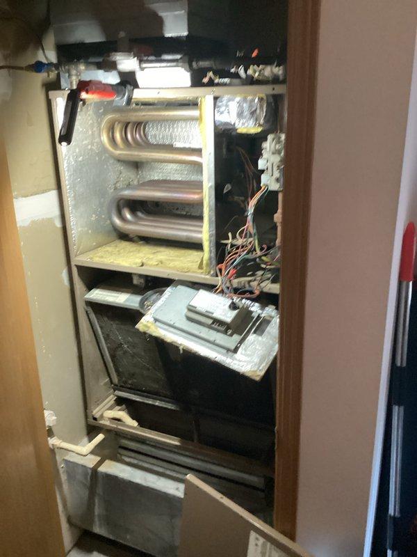 Responded to service call for Magicpak-179 unit with water leakage affecting the unit below. Performed inspection of both sides of the vertical stack HVAC system installed in confined utility space. Examined serpentine heat exchanger coils showing heat discoloration and inspected condensate drainage system including white PVC piping. Identified source of water intrusion and cleared condensate drain line blockage to resolve leakage issue. Verified proper drainage flow, checked air handler components, and confirmed system operation. Unit restored to normal function with no further water discharge into lower unit.